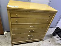 Chest of 4 drawers shown with two top drawers having round knobs and three lower drawers with horizontal pull handles, blonde solid wood finish.