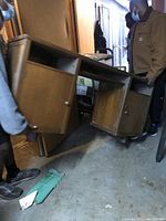 Two people moving the heavy solid wood credenza, showing its size and sturdy construction with storage cabinets on each side.