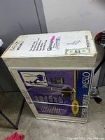 Photo of the original shipping box for Weslo Elliptical Glider 2.0 exercise machine showing box condition and size comparison with a dollar bill.