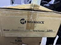 Cardboard shipping box with McCormack branding, model Micro Headphone Drive and serial number visible