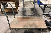 Photo showing full top view of the large metal utility cart with flat platform and tubular handle, with visible rust and discoloration on the surface.