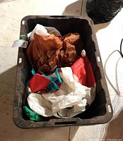 Three Christmas inflatables folded inside a black rectangular tote container.