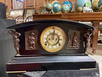 Full front view of Ansonia mantel clock showing black curved top design, side figurines, and clock face with ornate gold bezel.