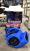 Two B-Air Vent VP-20 fans in original boxes, one fan taken out and placed on floor showing front intake and side controls with power cord wrapped.