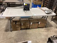Full view of folding table with plastic surface and metal legs, some items placed on top and underneath not included.