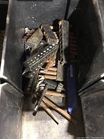 Inside view of drill bits, some rusted and arranged on black bit holders inside the storage compartment of the work station.