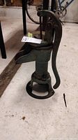Full view of the green cast iron hand pump with lever on top showing overall shape and condition.