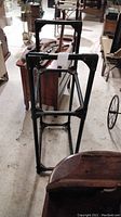 Full view of the black metal tire rack showing the rectangular frame with support bars, positioned on a concrete floor.