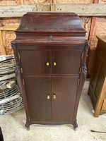 Front view of closed wooden cabinet with carved legs and brass knob hardware