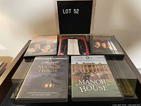 Six DVD movie cases shown on a flat surface including Gosford Park, Manor House, Four Weddings and a Funeral, and Secrets of Manor House.