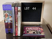 Photo showing the one VHS tape titled 'The Windsors: A Royal Family' and four DVDs with titles including 'Royal Britain from Heaven', 'Young Victoria', 'The British Empire in Colour', and 'Pageantry of the Crown'. Items are arranged standing and flat on a reflective surface.