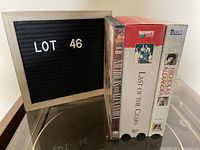 Photo of three media items including one DVD and two VHS tapes with their spines visible showing titles and brands.