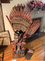 Front view of full statue with a removable feather piece on floor