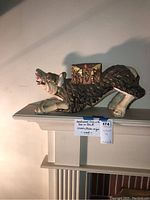 Full side view of crouching foo dog with box on back displayed on mantel