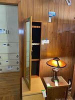 Jewelry wall cabinet closed showing wooden frame and full-length mirror on the door.