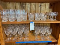 Photo showing Mikasa Old Dublin wine glasses (stemmed), water glasses and highball glasses on wooden shelves with intricate glass cuts and designs.