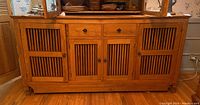 Front view of the solid wood sideboard buffet showing its four slatted doors and two drawers with metal ring pulls.