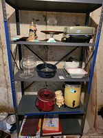 Photo of metal shelving unit displaying various kitchen items including Austrian stein, electric roaster, glass bowl, roasting pans, crock pot, soup crocks, and coffee maker