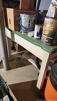 Full view of wood base table with green enamel top, showing rust from paint cans on top and mildew on base.