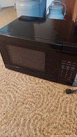 Front and side view of black GE microwave JES0737DNBB showing control panel and window.