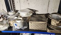 Wide photo of Noritake Lorina china on shelving including plates, cups, boxed items, and bowls, in basement setting.