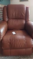 Front view of brown leather recliner chair, showing padded back, seat, and armrests with visible stitching.