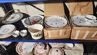 Multiple plates, cups and bowls on shelving including floral and bird designs