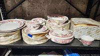 Full shelf view with stacked vintage Johnson Bros Devonshire china including plates, bowls, and covered serving pieces in their original cloth storage wraps.