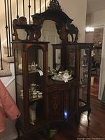 Full front view of antique mirrored etagere and china display cabinet showing two side glass display shelves, central cabinet door, and mirrored back