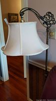 Side profile of the lampshade with bridge arm showing ornate scrollwork in brass and bronze finish.