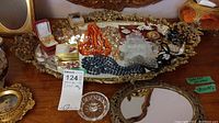 Overall view of the costume jewelry on an ornate tray showing various necklaces, pins, earrings, and bracelets.