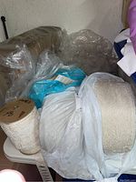Group of three lace trim spools—two large off-white and one medium-width—placed on table with plastic bags