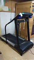 Side view of treadmill showing frame, running belt and handrails