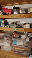 Four wooden shelves filled with clear plastic containers holding sewing fabric, cords, threads, and sprays.