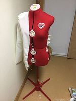 Front view of red Singer 150 dress form with white muslin drape and adjustment dials visible