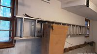 Full side view of aluminum extension ladder showing its length and number of rungs, leaning against a wall in a garage.
