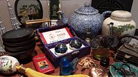 Wide shot of the Asian decor lot showing porcelain, teapot, cast iron box, bowls, glass bird, Baoding balls, and other small decorative items.