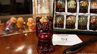 Photo showing mini resin monk figurines including a dark red Laughing Buddha with arms raised.
