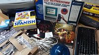 Overview of boxed PC game titles, language book, home automation system, cables, and electronic items.