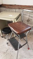 Vintage Cosco wooden seat step stool front angle showing wooden seat, metal frame and step surfaces