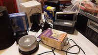 Photo showing multiple electronics including boxed Tower Clock Radio, Sony Video Print Pack, cassette recorder, music light, and cables.