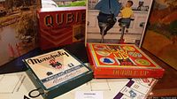 Photo showing the Monopoly Popular Edition, Dubble Up, and Qubic board game boxes displayed upright
