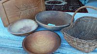 Three wooden bowls, weaving basket and carved wooden cutting board shown from a side angle on carpeted stairs.