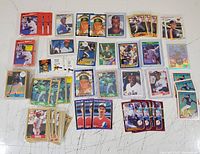 Top-down photo showing 45 assorted 1980s-1990s baseball cards laid out on a table including players in different poses, some in protective sleeves.