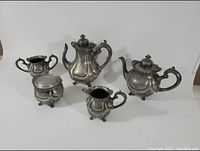 Photo showing full tea set of teapot, coffee pot, sugar bowl, and creamer arranged together