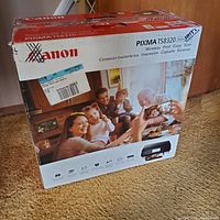 Boxed Canon Pixma TS8320 printer showing brand and model with family photo on packaging.
