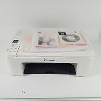 Front view of Canon TS3122 printer with manuals and CD on top