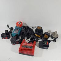 Photo showing multiple battery chargers and batteries from brands including DeWalt and Black & Decker, cables attached.