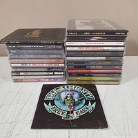 Photo showing two stacks of rock CDs with visible album titles and a CD booklet in front featuring Pearl Jam 'Free & Easy'.
