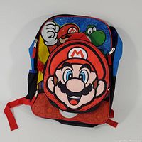 Front view of the Super Mario backpack showing characters Mario, Luigi, and Yoshi with front pocket featuring Mario face.